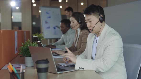 Male Operator with Laptop Talking with Customer in Headset