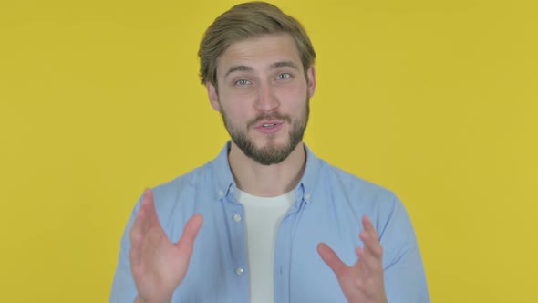 Young Man Talking on Online Video Call on Yellow Background