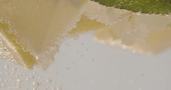 Slow Motion Macro Shot of a Lemon Slice in Water Bubbles Drinking Cold Lemonade