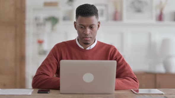 African Man Working on Laptop in Office