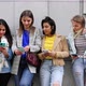Multiethnic Group of Beautiful Young Female Friends Standing Against a Wall Using Mobile Smartphones - VideoHive Item for Sale