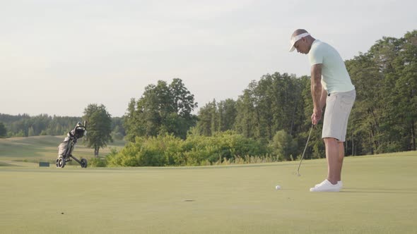 Handsome Successful Middle Eastern Golfer Swinging and Hitting Golf Ball on Beautiful Course