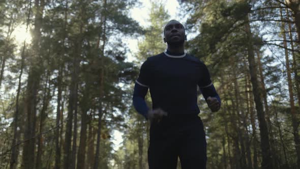 Young Fit African American Male Jogging on a Forest Road.