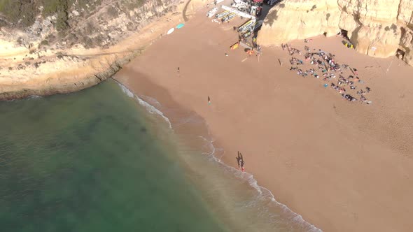 Tourists enjoying a beautiful day in the beach of Benagil, Portugal on a bright sunny day - Aerial s