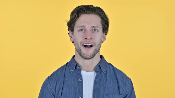 Yes Young Man Shaking Head in Acceptance on Yellow Background