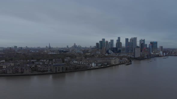 Wide falling drone shot of London skyline from Canary wharf cloudy