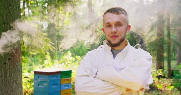 Apiary in the Middle of the Forest Male Young Bearded Handsome Beekeeper in White Protective Suit