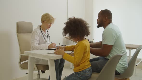 African American Father with Cute Little Boy Visiting Doctor in Medical Clinic