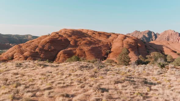 Orbiting aerial of dead brush surrounding a hill in Utah's Snow Canyon.