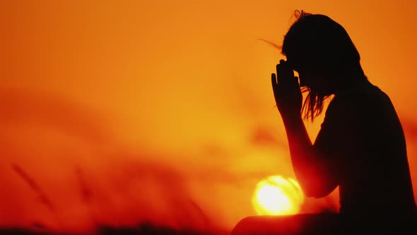 Profile of a Woman in Prayer at Sunset