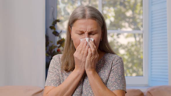 Ill Mature Woman Blowing Running Nose Sitting on Couch