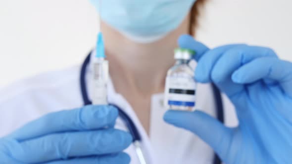 Doctor's with Face Mask Holds a Syringe and a Vaccine Ampoule at the Hospital