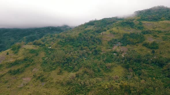 Drone footage flying towards a hillside in a valley covered in forest in central Cebu in the Philipp