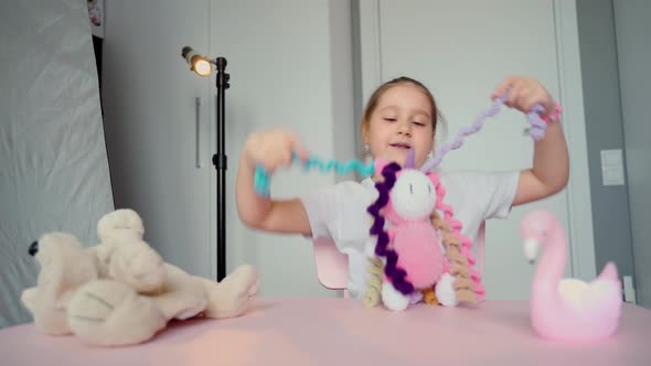 View from the camera of a cute girl child blogger talks about a knitted toy and plays with it