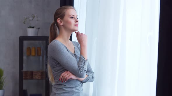 Young  girl is standing in front of the window