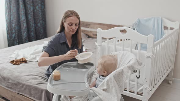 Young Mother Feeding Toddler