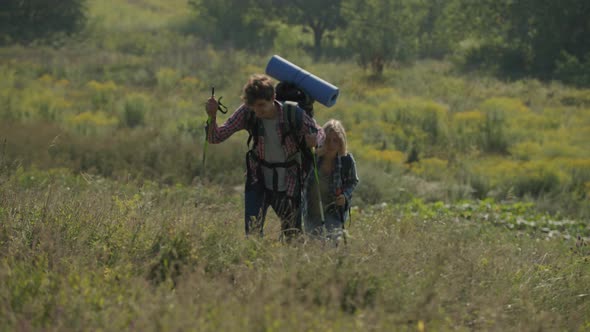 Young Family Hiking Holding Trekking Poles Early in the Summer Morning