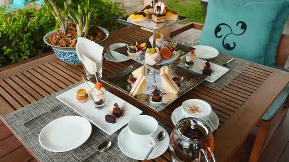 Tea Set and Coffee with Assortment of Pastries in Outdoor Cafe