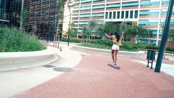 Pretty Athletic Girl Rides a Longboard in Modern City