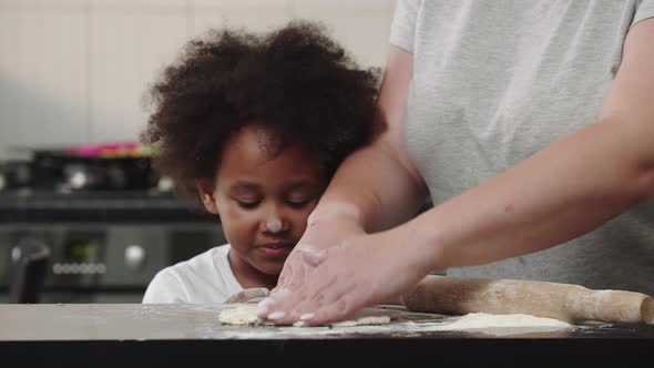 Black Little Smiling Girl Tasting a Piece of Raw Dough