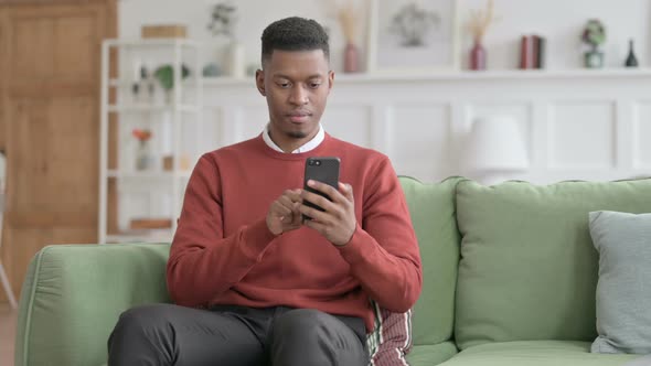 African Man having  Success on Smartphone at home