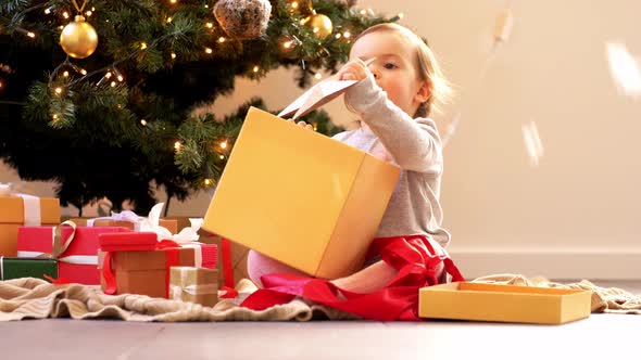 Happy Baby Girl Opening Christmas Gifts at Home