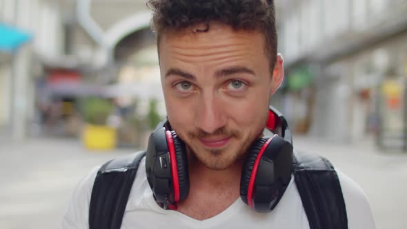 Portrait of Young Man Listening Music From His Smartphone in Red Headphones on Street of Town Center