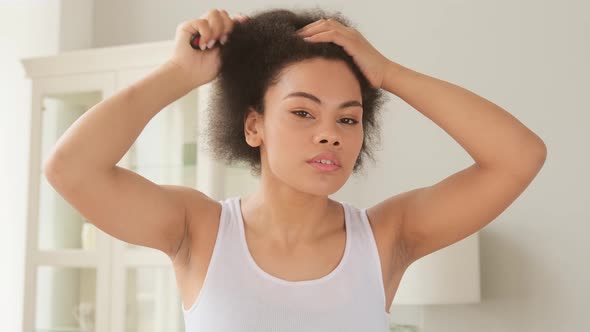 African american woman combing her hair with hairbrush, makes hairstyle