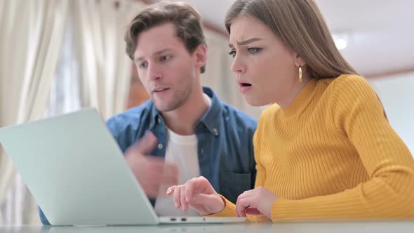 Disappointed Office Colleagues Reacting to Loss on Laptop