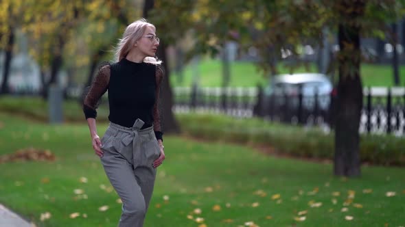 Sexy Blonde Woman Is Walking on Street of City at Early Autumn, Moving Passionately and Smiling