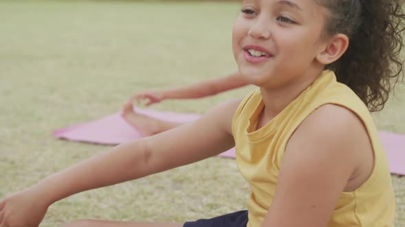 Video of focused diverse girls stretching on mats in front of school