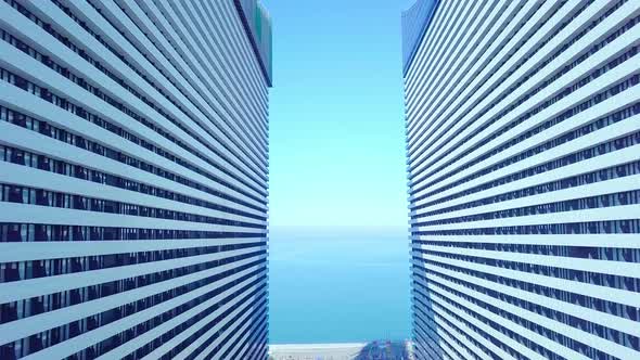 the drone flies between two buildings with glass windows.