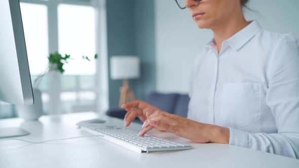 Woman with Glasses Typing on a Computer Keyboard. Concept of Remote Work.