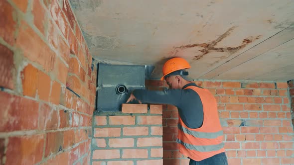 The Master on the Construction Site Builds a Ventilation Channel with Red Brick
