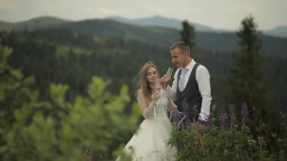 Groom with Bride Drink Champagne on a Mountain Hills. Wedding Couple. Family