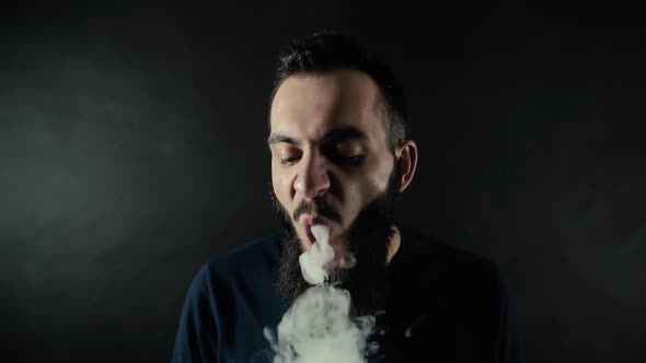 Close-up Portrait of Bearded Man Vaping Many Small Steam Circles To Camera