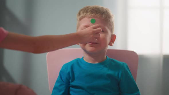 Girl Hand Glues Dot Stickers on Boy Nose at Home Closeup