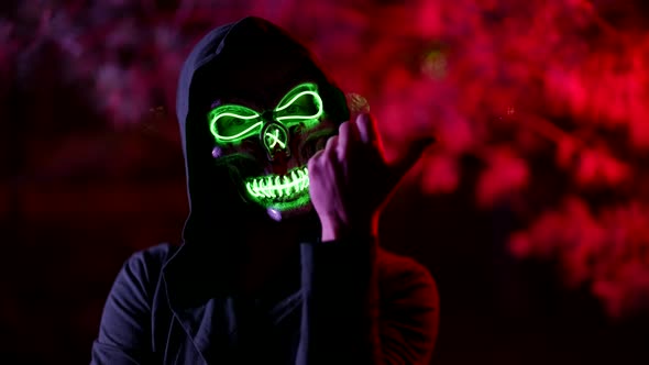 Portrait of a Person in a Terrible Glowing Mask of Death and in a Hood Against a Background of