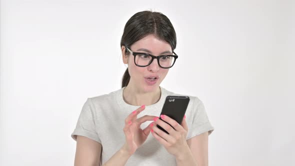 Excited Young Woman Looking at Phone and Celebrating on White Background 