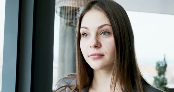 Portrait of Young Attractive Female Who Looking at the Camera on the Office Near Window. Cheerfully