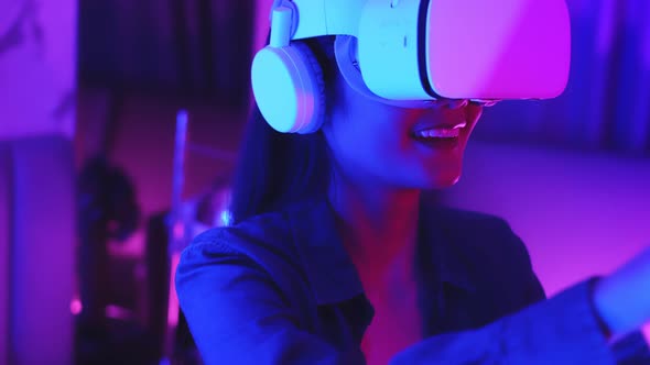 Young asian woman is using virtual reality headset. Neon light studio portrait.