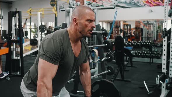 Concentrated Millenial Bald Muscular Guy Lifting a Heavy Barbell Using His Triceps Muscles