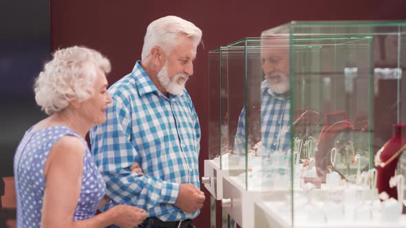 Happy Aged Couple Standing Near Showcase with Jewelry