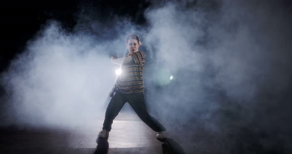 Teenage dancer performing hip hop dance in slow motion with strobe light and smoke background