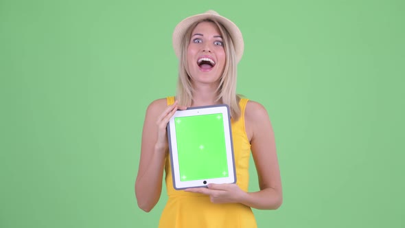 Happy Young Blonde Tourist Woman Talking While Showing Digital Tablet