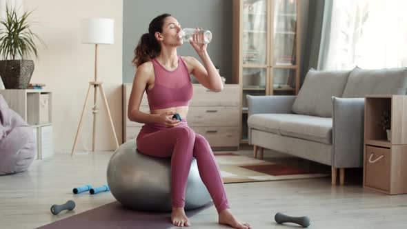 Woman Drinking Water Sitting on Fitball