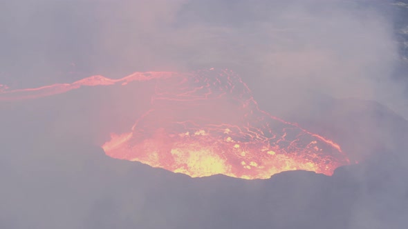Close Up Of An Erupting Volcano Crater With Boiling Lava And Toxic Smoke. aerial tilt down