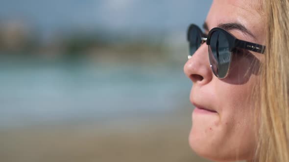 Face of a Blonde-haired Girl in Dark Sunglasses Licking Beautiful Lips