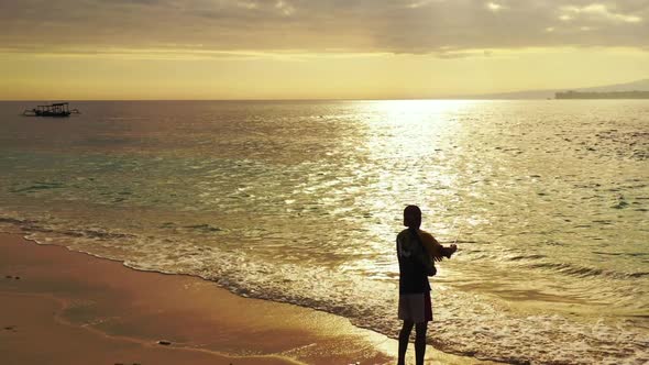 Single male angling on perfect sea view beach break by blue lagoon and bright sandy background of Lo