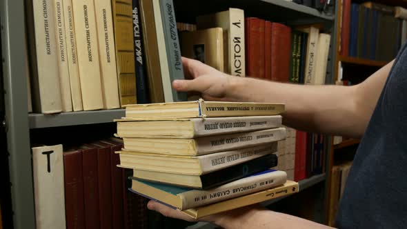 Man Puts The Books On The Shelf In Library